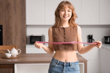 Mutfakta göğüslerini ölçen güzel bir genç kadın. Kilo verme konsepti