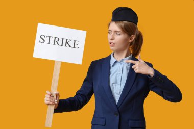 Sarı arka planda STRIKE yazısıyla pankartı gösteren kadın hostes protestosu