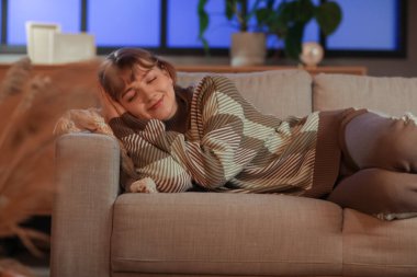 Oturma odasında rahat bir kanepede uyuyan genç bir kadın.