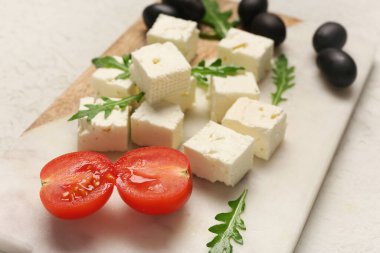 Beyaz arka planda peynirli, roka, vişneli domates ve zeytinli pano.