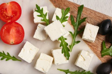 Beyaz arka planda peynirli, roka, vişneli domates ve zeytinli pano.