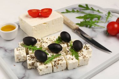 Lezzetli peynirli pano, beyaz grunge arka planda siyah zeytin ve domates.