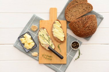 Beyaz ahşap arka planda taze tereyağı, sarımsak ve biberli ekmek dilimleri.