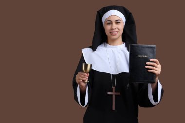 Kahverengi arka planda İncil ve kadehle genç rahibenin portresi
