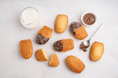 Lezzetli madeleinler, beyaz arka planda çikolata kremalı kaşık ve kase.