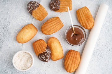 Lezzetli madeleineler, beyaz grunge arka planda çikolatalı kağıt ve kase.