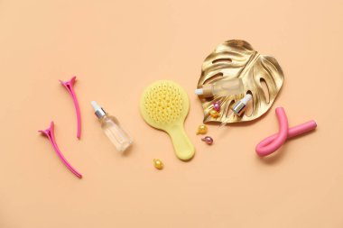 Turuncu arka planda saç fırçası, klipsleri ve kozmetik ürünleri şişeleri