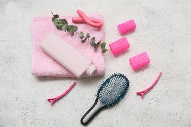 Saç fırçası, saç tokaları ve beyaz grunge arka planda bir şişe şampuan.