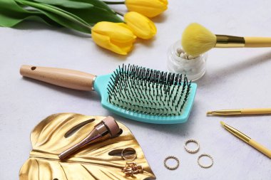 Makyaj ürünleriyle saç fırçası ve beyaz arka planda lale çiçekleri