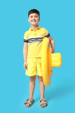 Mavi arka planda şişme yüzüğü olan şirin bir çocuk.