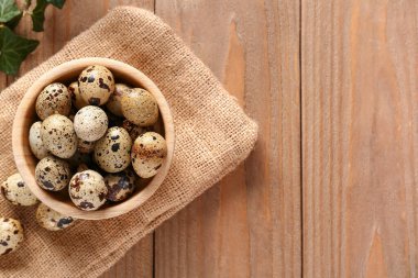 ahşap zemin üzerinde taze bıldırcın yumurtası ile kase