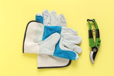 Sarı arka planda eldivenleri olan yeşil kesiciler.