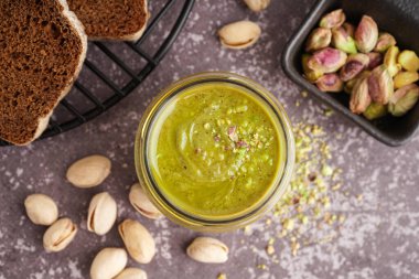 Gri grunge arka planında ekmek dilimleri olan bir kavanoz fıstık ezmesi.