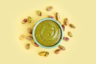 Sarı arka planda fıstık ezmeli bir kase.