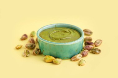 Sarı arka planda fıstık ezmeli bir kase.