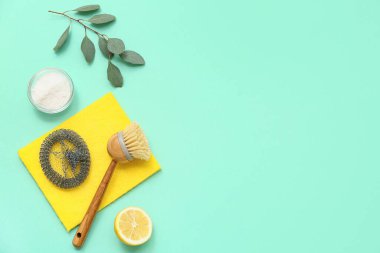 Renkli arka planda bir kase kabartma tozu, limon ve temizlik malzemesiyle kompozisyon
