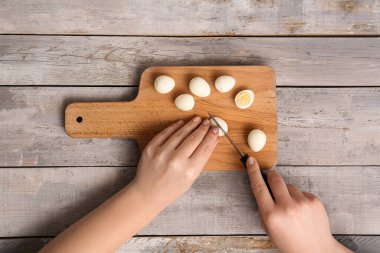 Ahşap masada haşlanmış bıldırcın yumurtası kesen kadın.