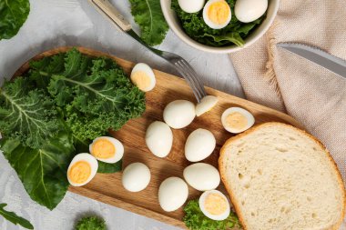 Kaynamış bıldırcın yumurtalı ahşap tahta, açık arkaplanda bir parça ekmek ve yeşillik.