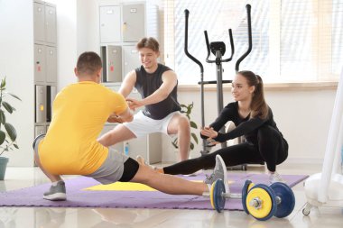 Male coach training young people in gym
