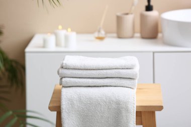 Modern banyonun iç tarafındaki ahşap masanın üzerinde temiz, yumuşak havlular yığını.