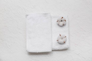 Temiz yumuşak havlular ve beyaz arka planda pamuk çiçekleriyle güzel bir kompozisyon.
