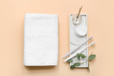 Temiz yumuşak havlular, taş tepsi, pamuk yastıklar ve bej arka planda diş fırçaları ile kompozisyon