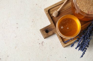Beyaz grunge arka planda bir bardak tatlı bal ve kurutulmuş lavanta.