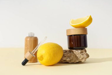 Limon, taş, kavanoz ve hafif arka planda bir şişe kozmetik ürünü içeren kompozisyon