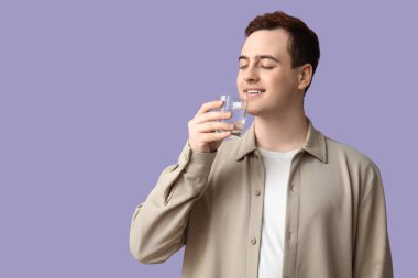 Leylak arkaplanda temiz su içen yakışıklı genç adam.