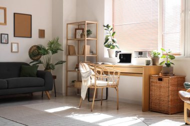 Çalışma odası, modern dizüstü bilgisayar, ev bitkileri ve koltuk.