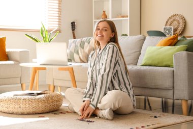 Oturma odasındaki kanepenin yanında oturan genç kadın.