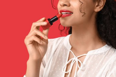 Genç Afro-Amerikalı kadın, arka planda kırmızı ruj sürüyor, yakın plan.