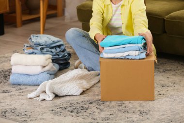 Evde kıyafet katlayan genç bir kadın.