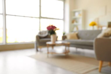 Oturma odası, koltuk, kanepe ve vazoda çiçekler.