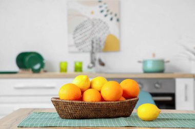 Mutfaktaki sepetin üzerinde turunçgiller var.
