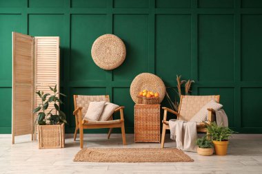 Yeşil oturma odasındaki rattan kutusunda turta olan hasır sepet.