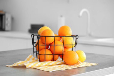 Beyaz mutfaktaki masada turunçgiller olan metal sepet.