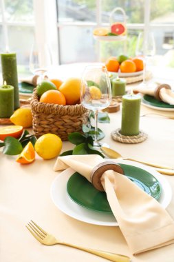 Oturma odasında turunçgiller, yanan mumlar ve yeşil yapraklarla dolu güzel bir masa.