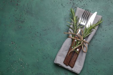 Yeşil grunge arka planda peçete, çatal bıçak ve biberiye ile şık masa ayarları