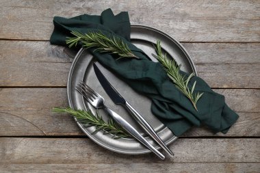 Ahşap arka planda peçete, çatal bıçak ve biberiye ile modern masa ayarları