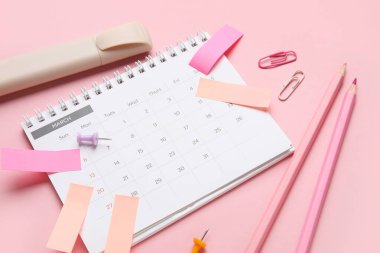 Pembe arka planda ofis kırtasiyesiyle takvim