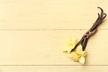 Güzel vanilya çiçekleri ve sarı ahşap arka planda sopalar.