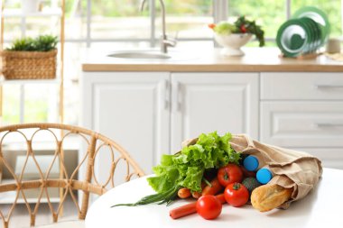 Mutfaktaki masada sebzeler, süt ve ekmek var.