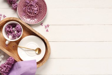 Beyaz ahşap arka planda leylak çiçekleri olan güzel bir masa.