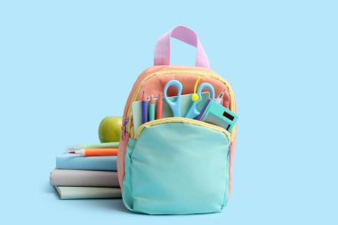 Kırtasiyeli Cyan okul çantası ve mavi arkaplan üzerine kitaplar
