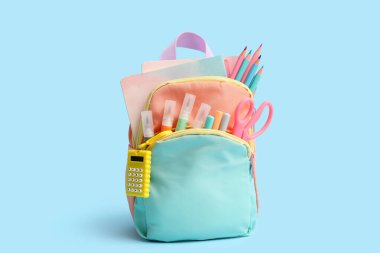 Kırtasiyeli Cyan okul çantası ve mavi arkaplan üzerine kitaplar