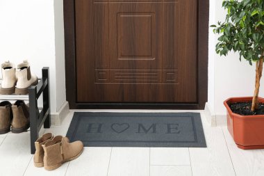 Koridordaki beyaz kattaki kapı eşiğinin yanındaki paspas.