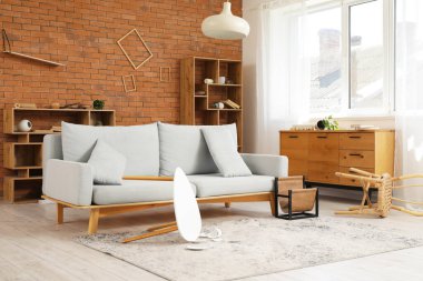 Hasarlı oturma odasının içinde kanepe ve deprem sonrası devrilmiş masa.