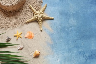 Mavi grunge arka planda şapka, kum ve deniz yıldızlarıyla güzel bir kompozisyon