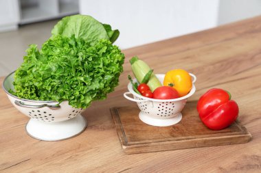 Ahşap mutfak tezgahında taze sebzeli Colander.